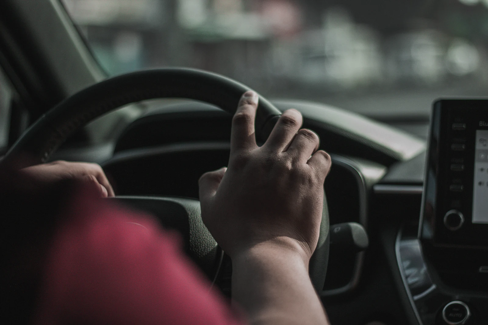 A driver's hands on the steering wheel of a car