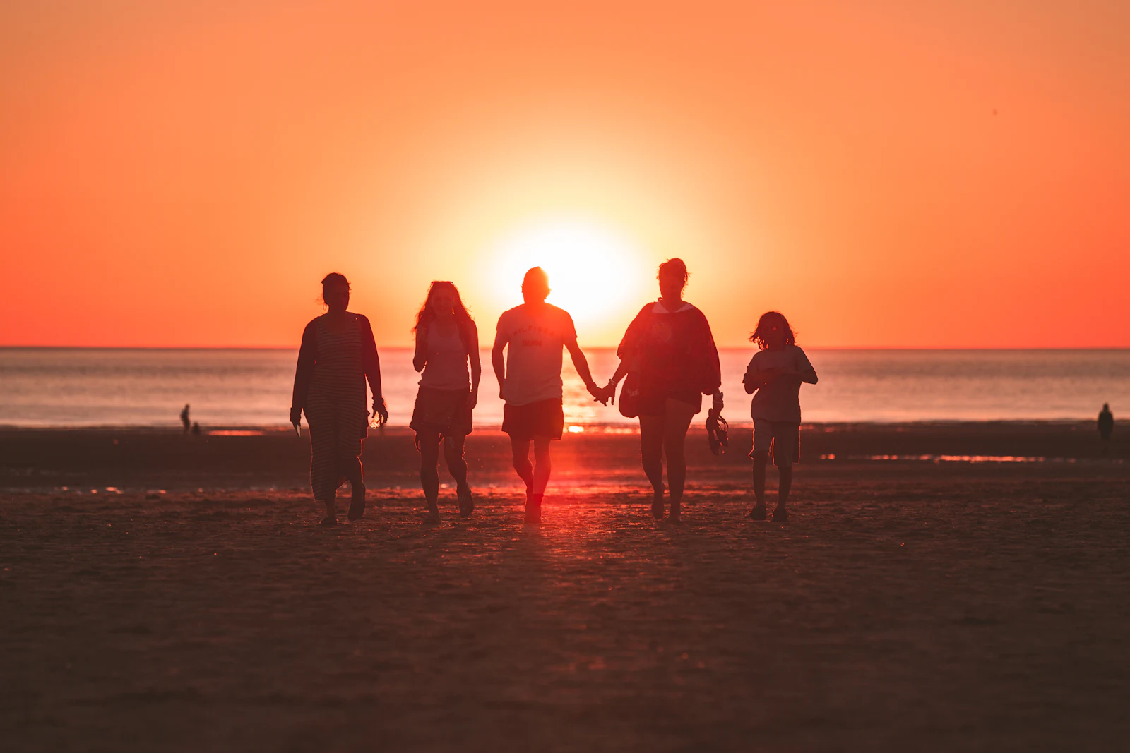 A group of friends walking together on a San Diego beach at sunset