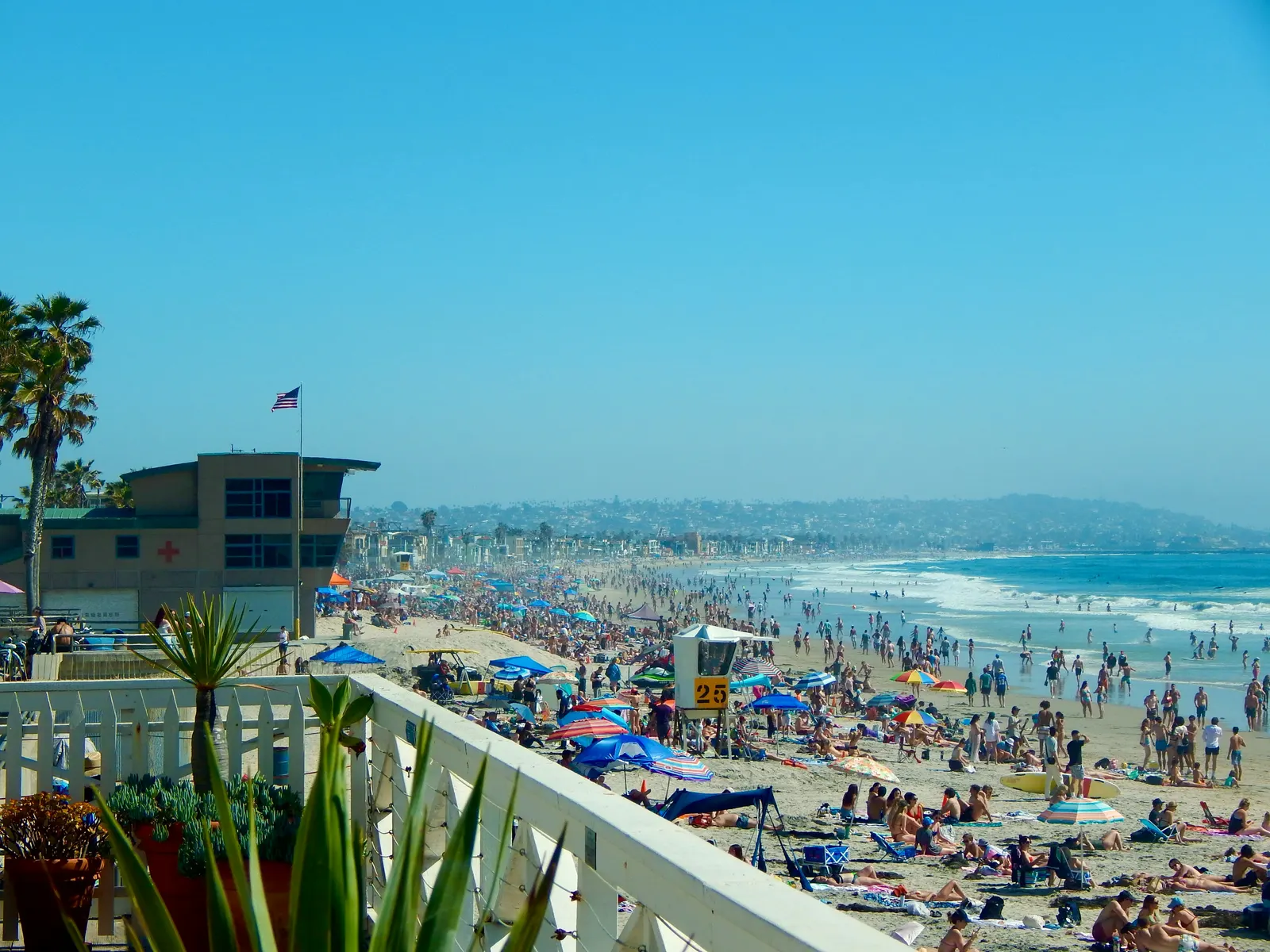 Crowded Pacific Beach on a sunny day with umbrellas and a lifeguard building