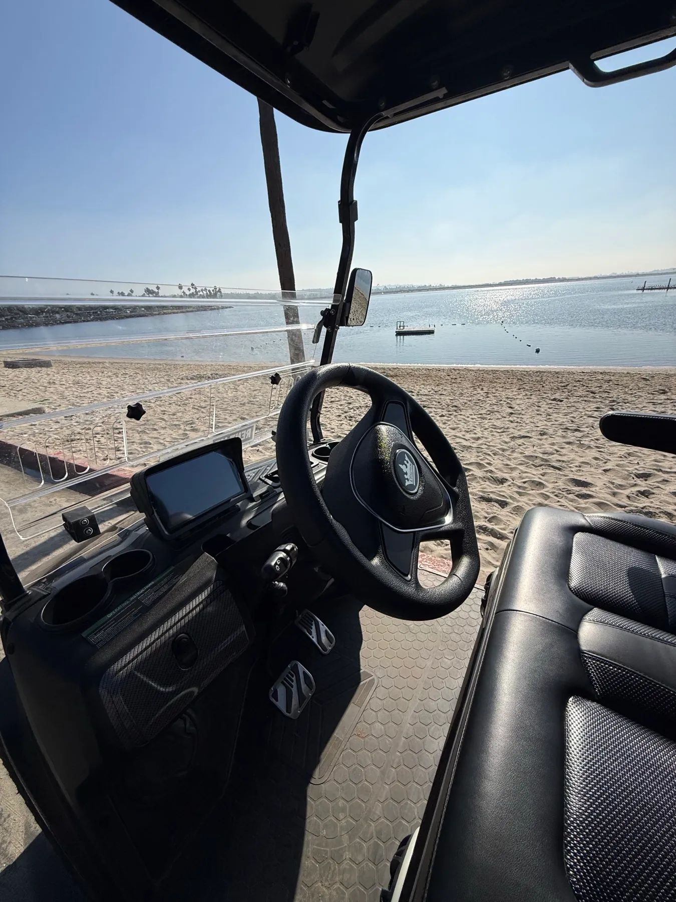 Black six-seat golf cart parked near the beach in San Diego